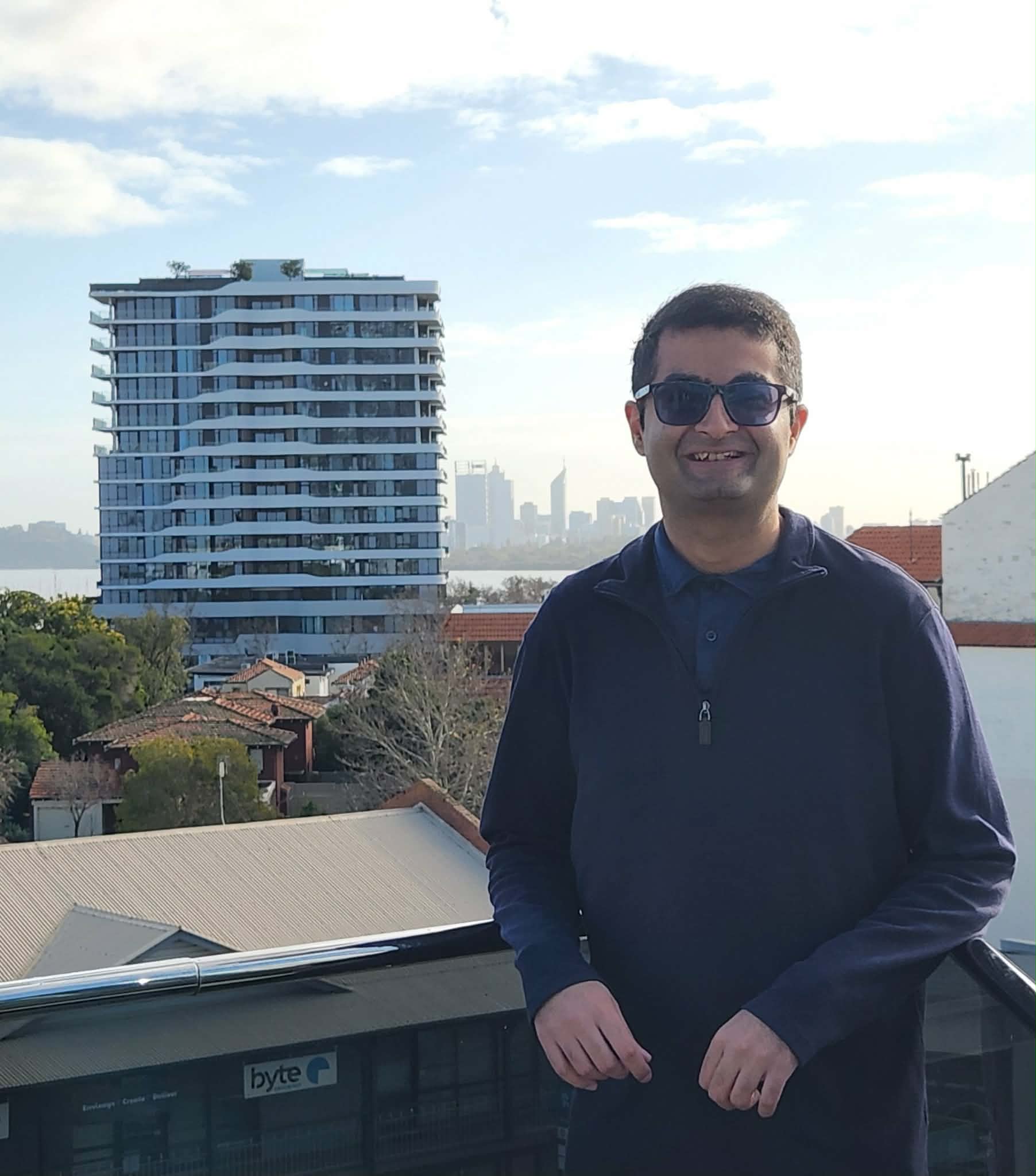 Anuj Sheta with the Precinct building and Perth skyline behind him